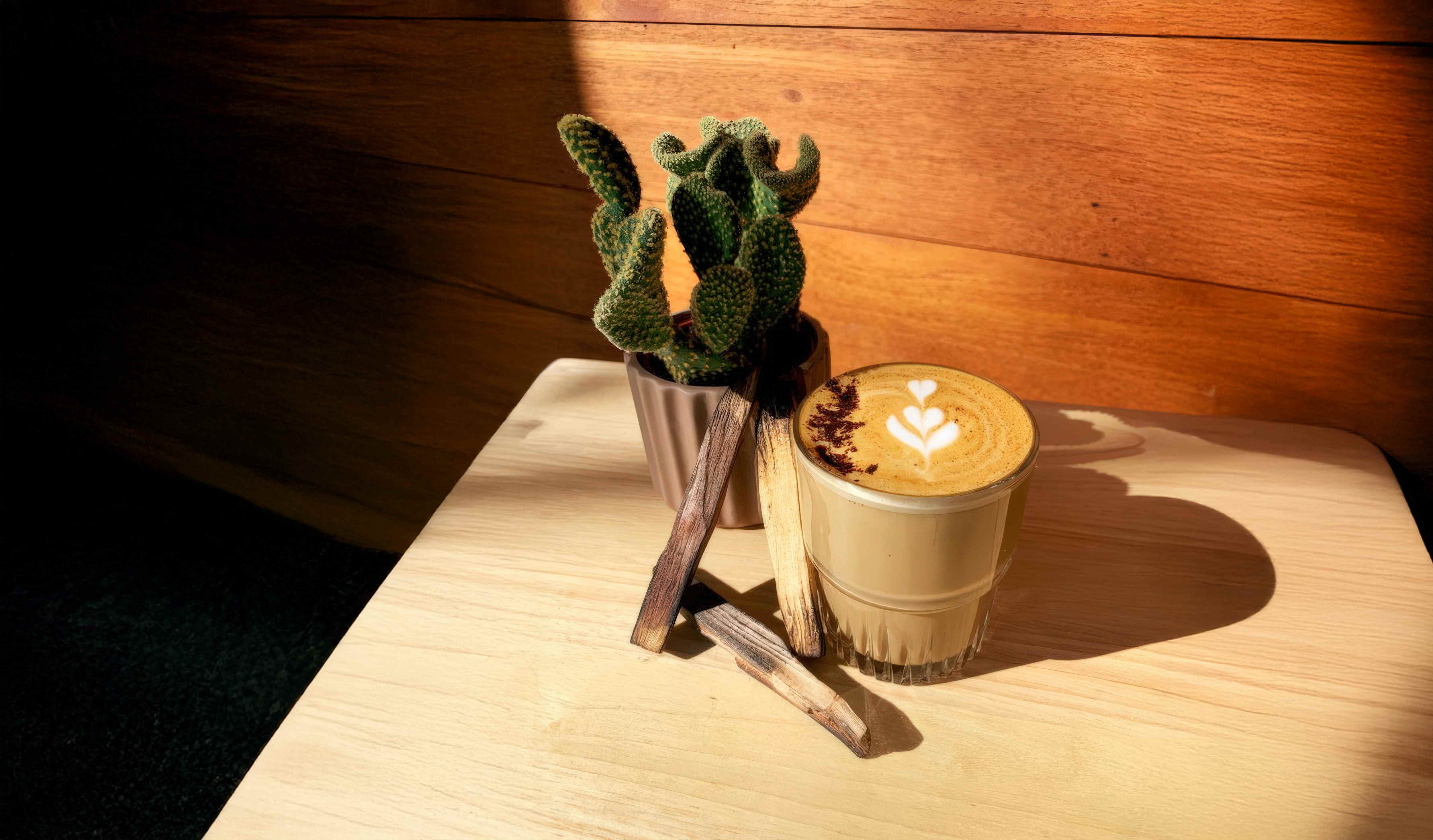 Coffee with latte art and a small cactus on a wooden table